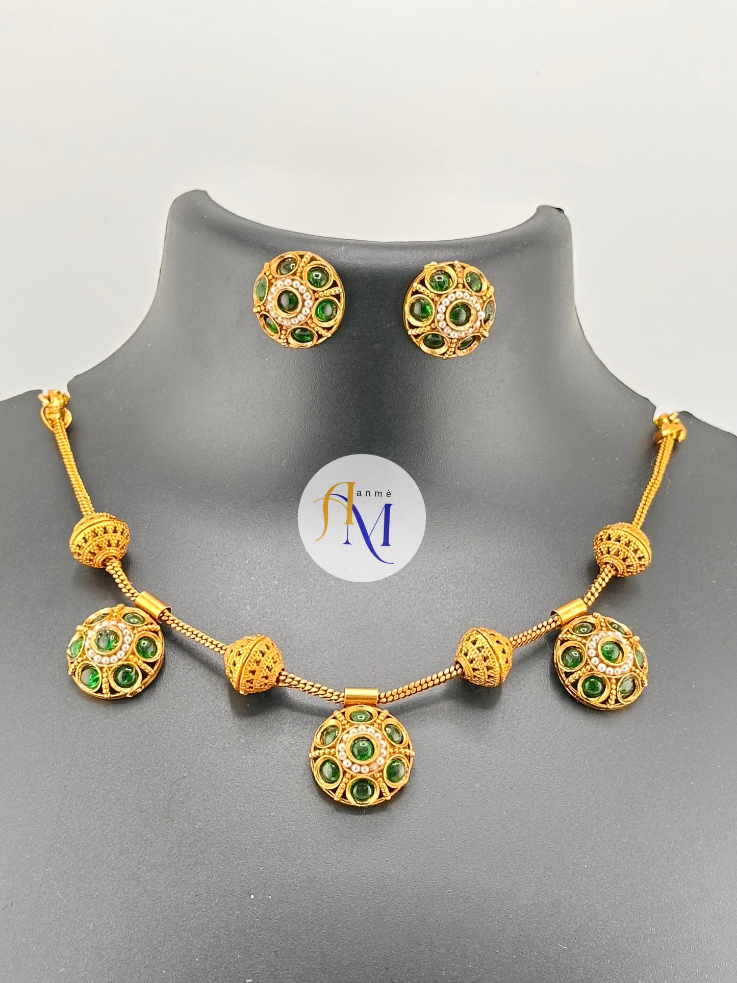 Traditional gold toned finish with ruby-green and white stones necklace set
