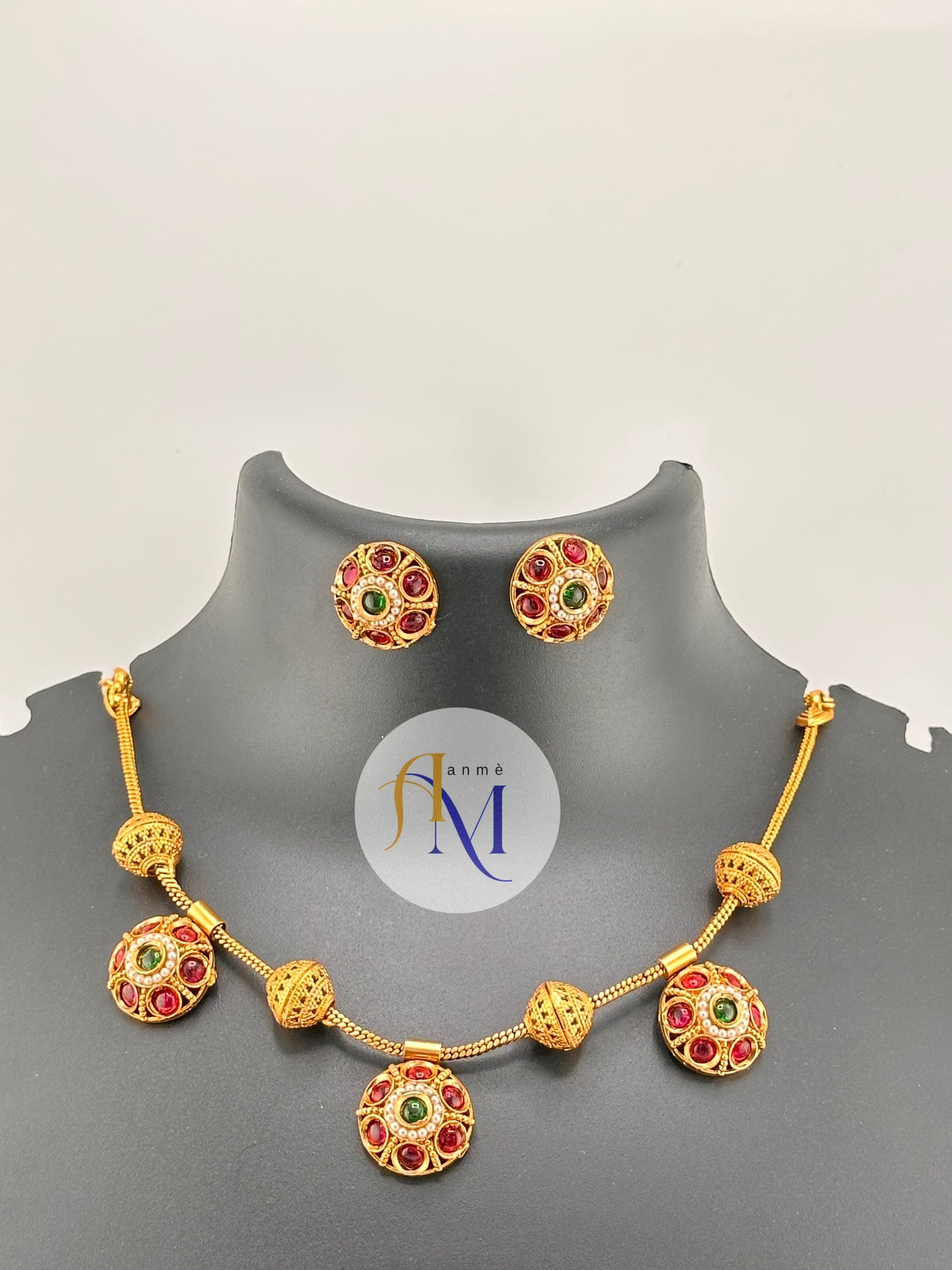 Traditional gold toned finish with ruby-green and white stones necklace set