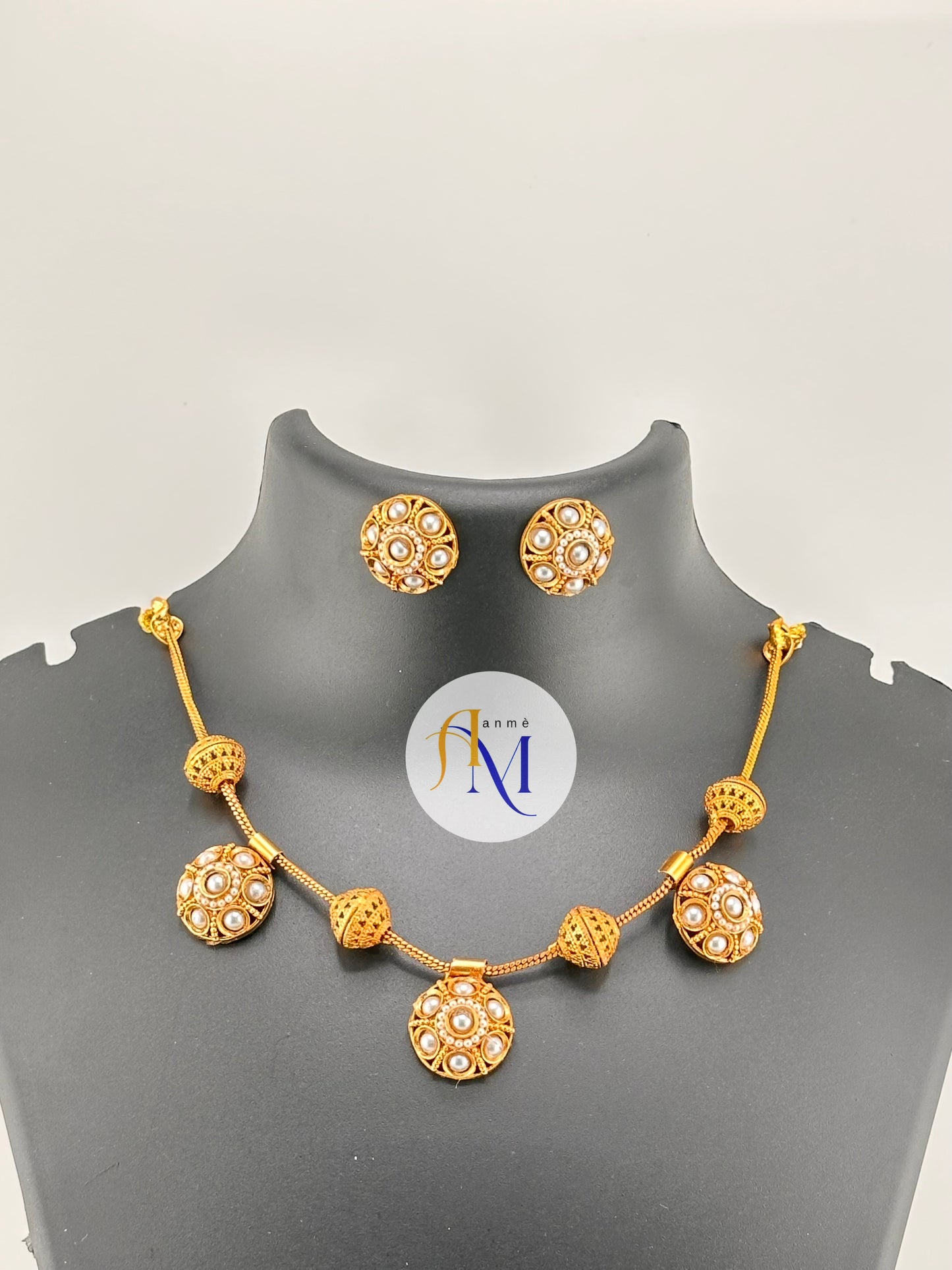Traditional gold toned finish with ruby-green and white stones necklace set