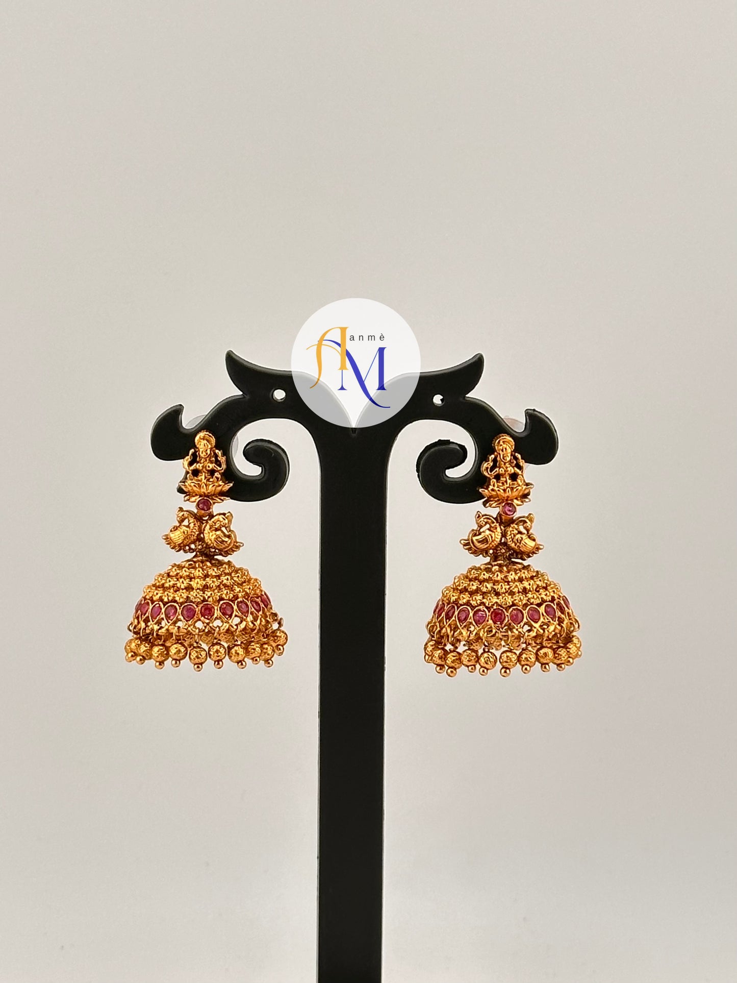 Simple temple design Jhumkas with Lakshmi, peacock and tiny floral motifs with ruby stones